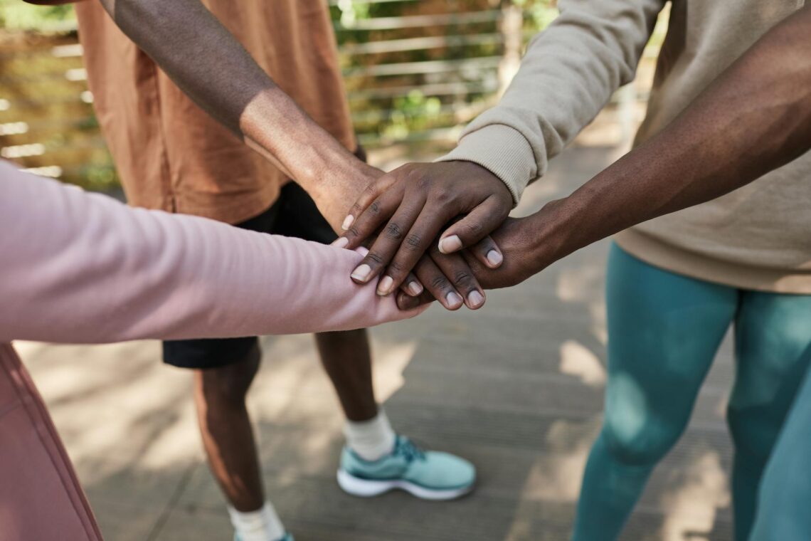 group of people standing with their hands in a huddle